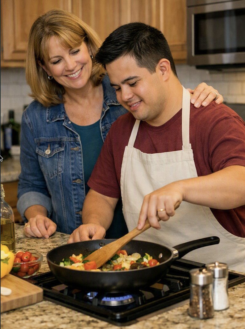 A young adult cooks vegetables on the stove at home while his mother stands beside him, watching rather than taking over.